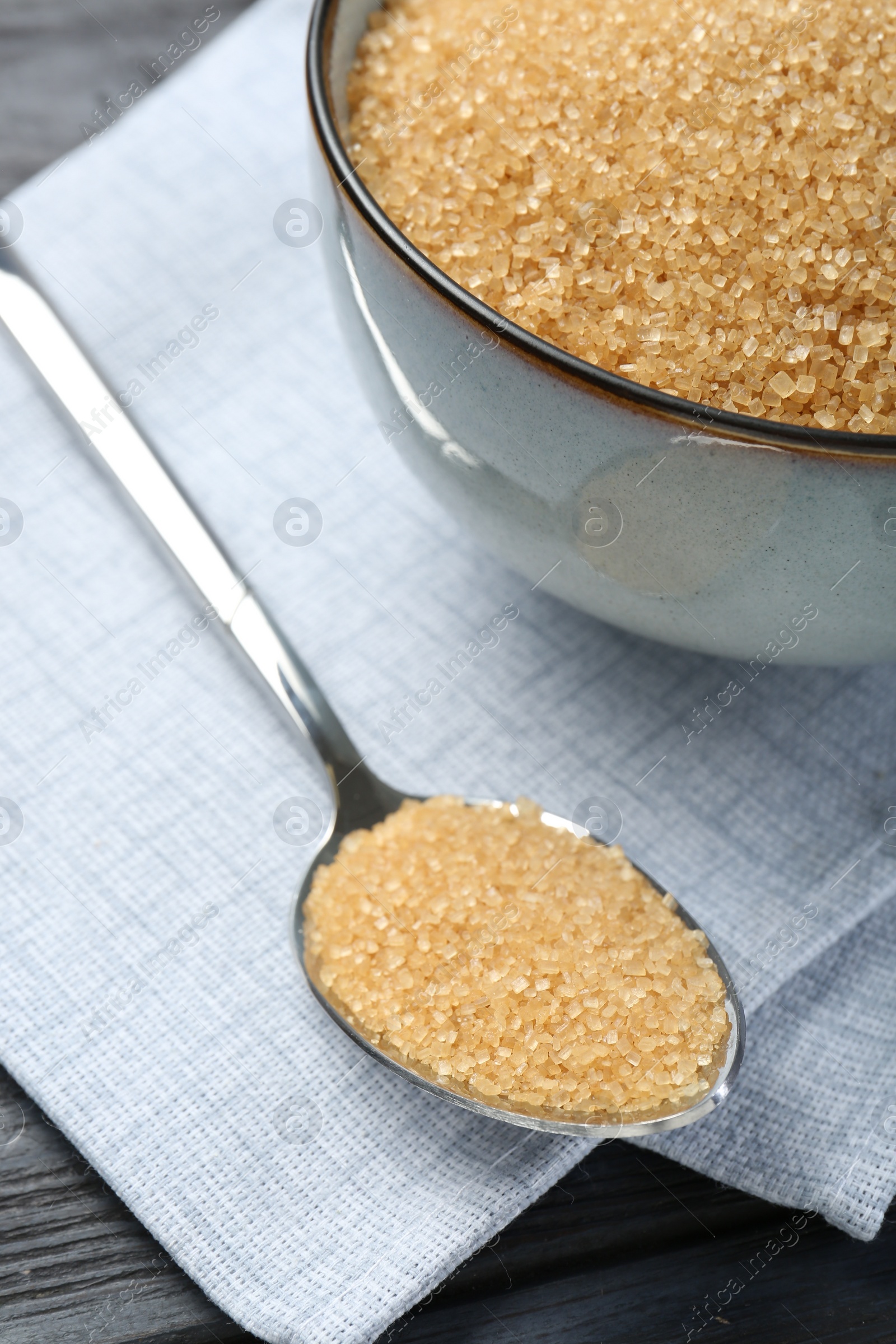 Photo of Brown sugar in bowl and spoon on table, closeup