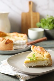 Piece of freshly baked rhubarb pie with cream cheese and mint leaves on grey wooden table