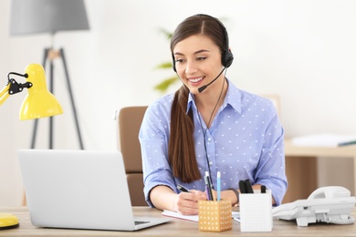 Young woman talking on phone through headset at workplace