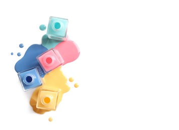 Photo of Spilled different nail polishes with bottles on white background, top view