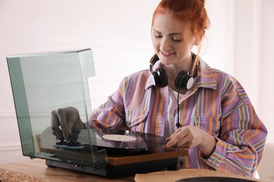 Photo of Beautiful young woman using turntable at home