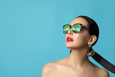 Image of Attractive woman in stylish sunglasses on light blue background. Palm leaves and sky reflecting in lenses. Space for text