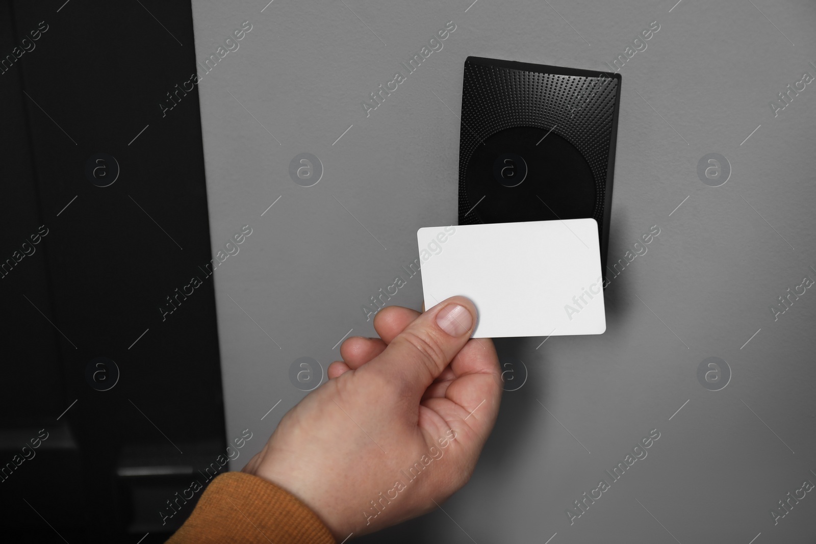 Photo of Man opening magnetic door lock with key card, closeup. Home security