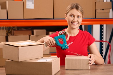 Photo of Post office worker packing parcel at counter indoors