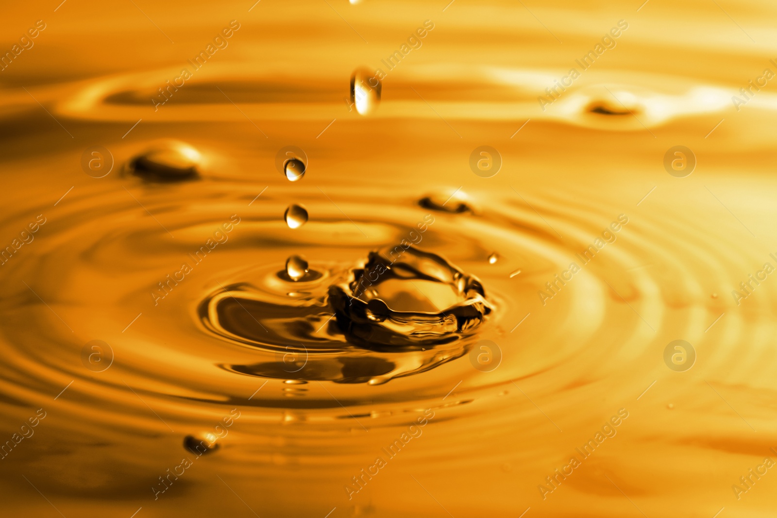 Image of Splash of golden oily liquid with drops as background, closeup