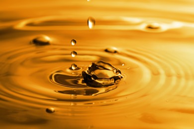 Splash of golden oily liquid with drops as background, closeup