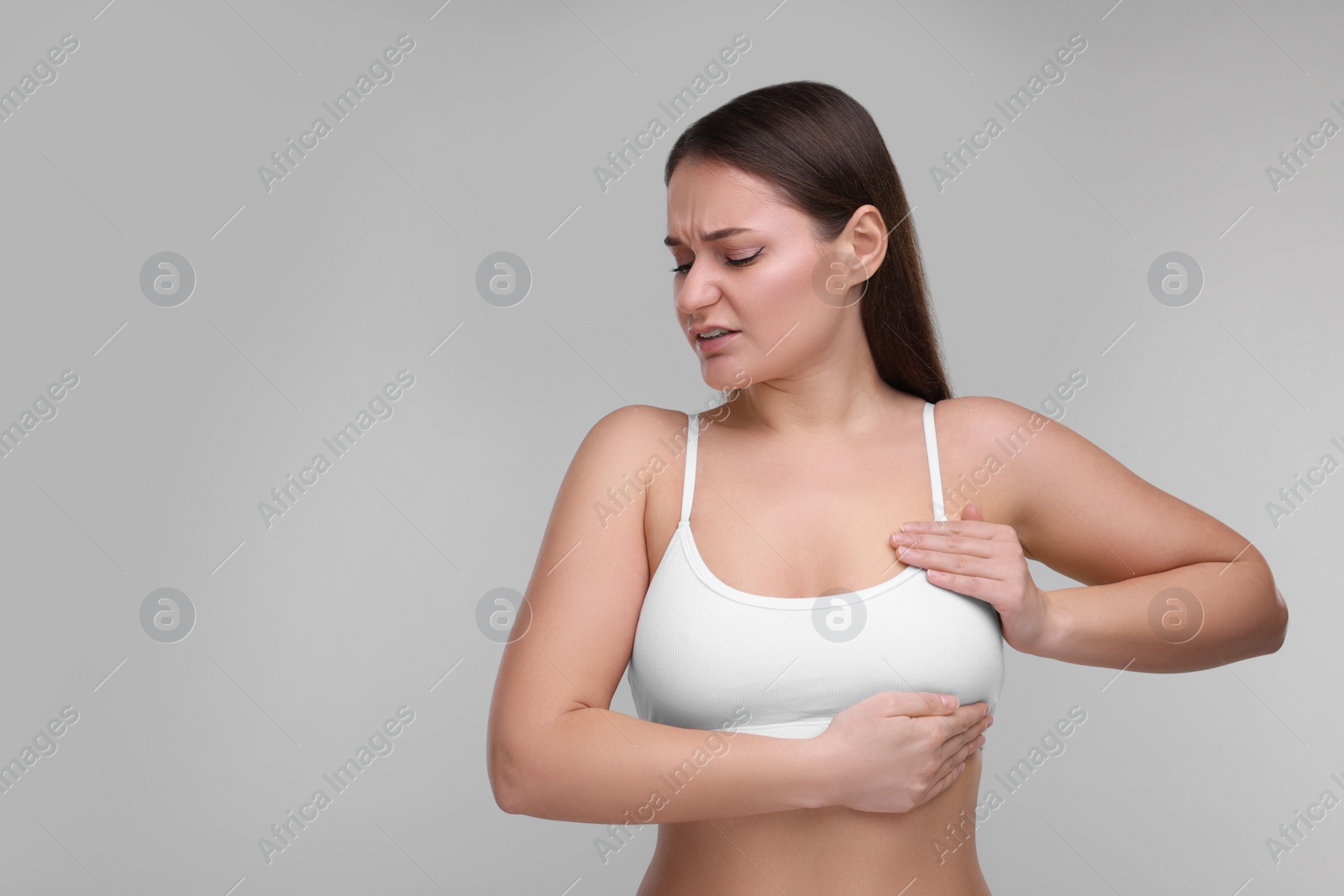 Photo of Mammology. Woman doing breast self-examination on light grey background, space for text