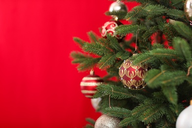 Photo of Beautifully decorated Christmas tree against color background, closeup