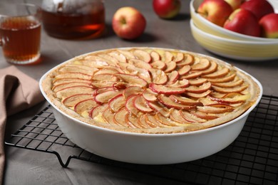 Photo of Tasty apple pie in baking dish on grey table