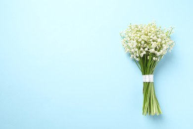 Photo of Beautiful lily of the valley bouquet on light blue background, top view. Space for text
