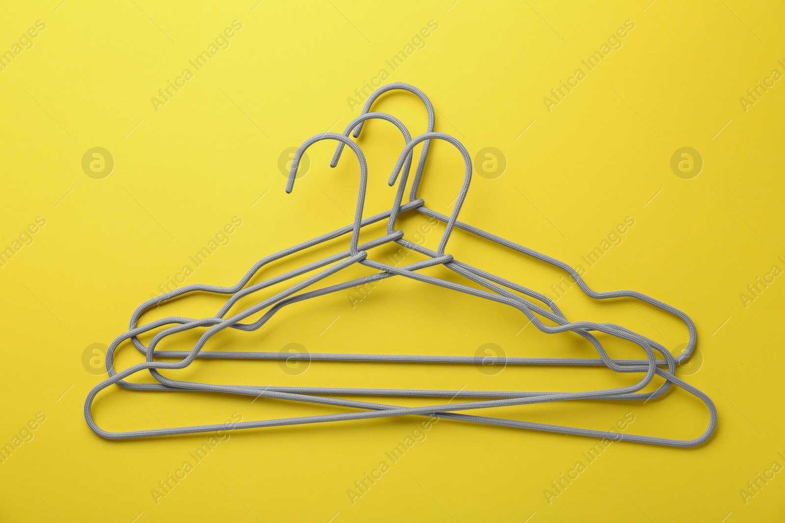 Photo of Many hangers on yellow background, top view