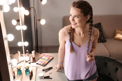 Portrait of beautiful woman with natural makeup near mirror indoors