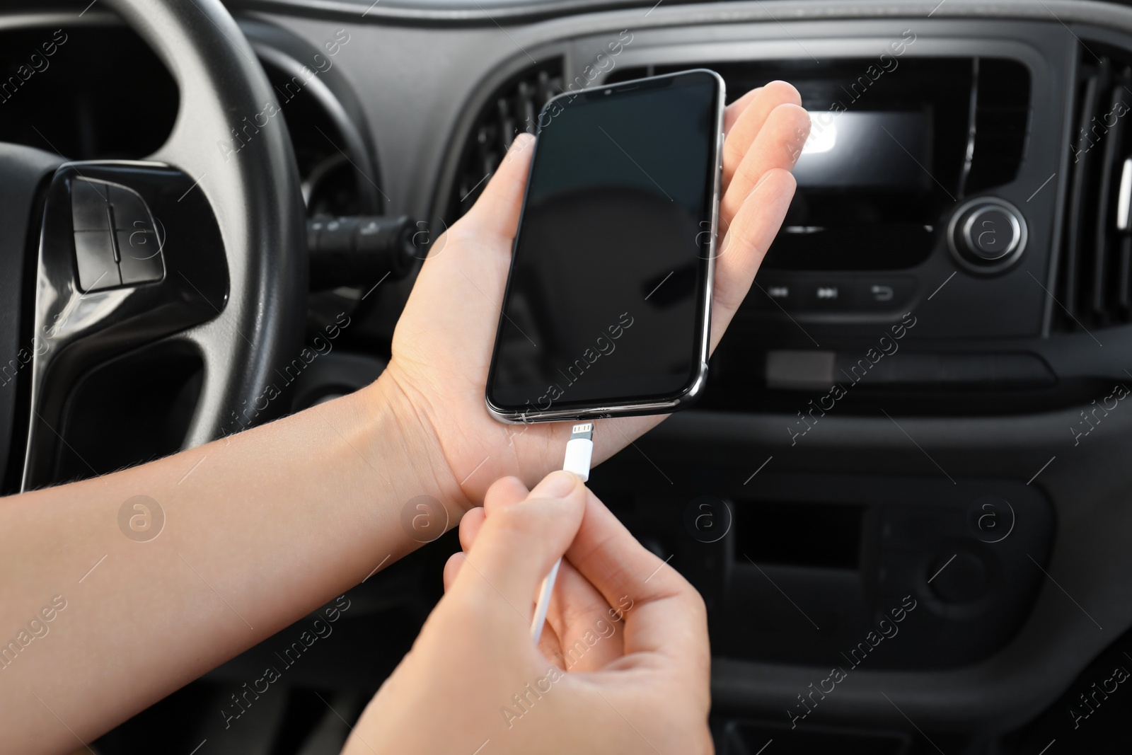 Photo of Person charging phone with USB cable in car
