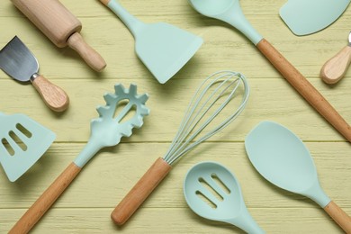 Photo of Set of different kitchen utensils on yellow wooden table, flat lay