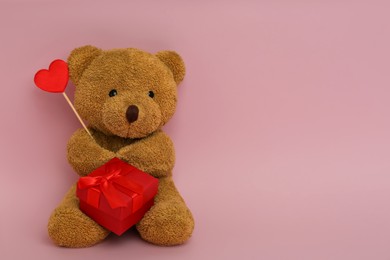 Photo of Cute teddy bear with red heart and gift box on pink background, space for text. Valentine's day celebration