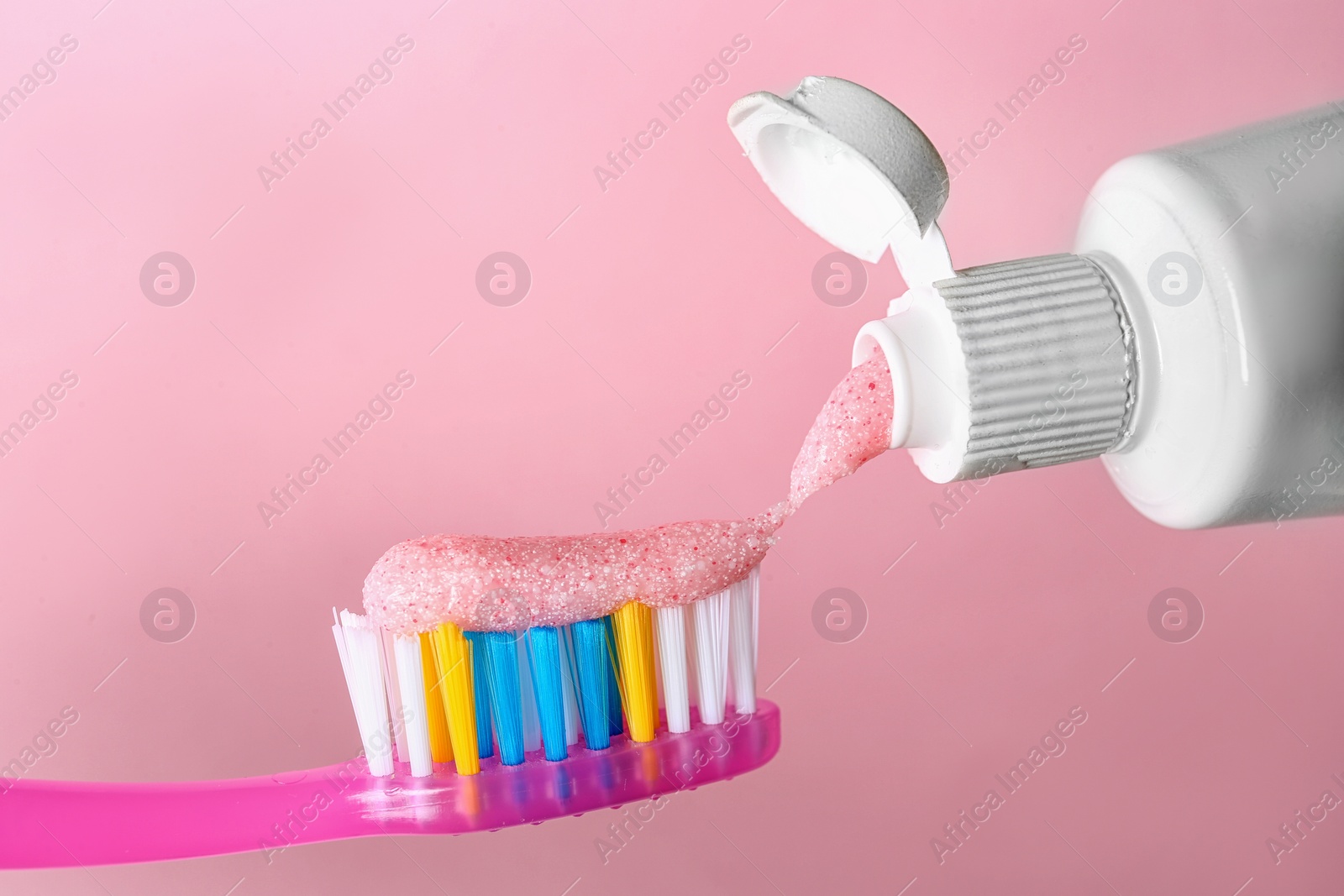 Photo of Applying paste on toothbrush against color background, closeup