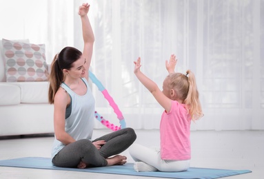 Sportive woman doing fitness exercises with daughter at home