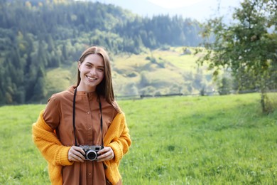 Photo of Happy woman with camera on meadow in mountains