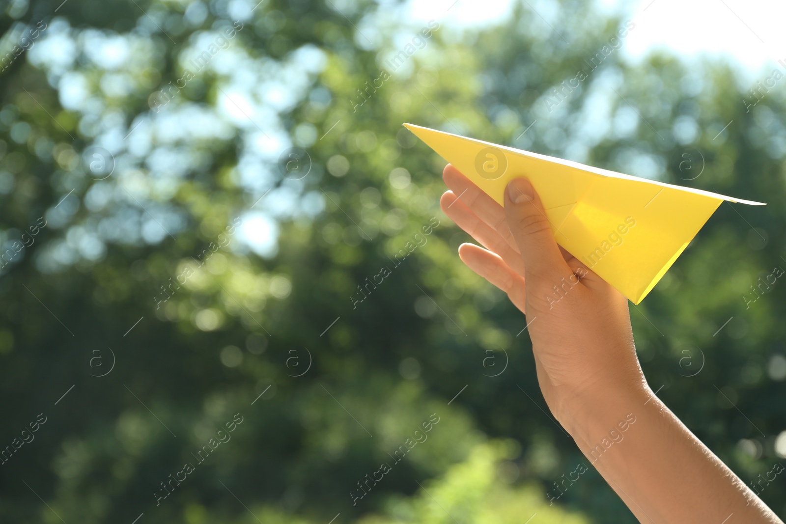 Photo of Woman holding paper plane outdoors, closeup. Space for text