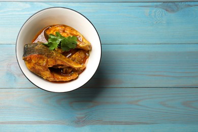 Photo of Tasty fish curry on light blue wooden table, top view. Space for text. Indian cuisine