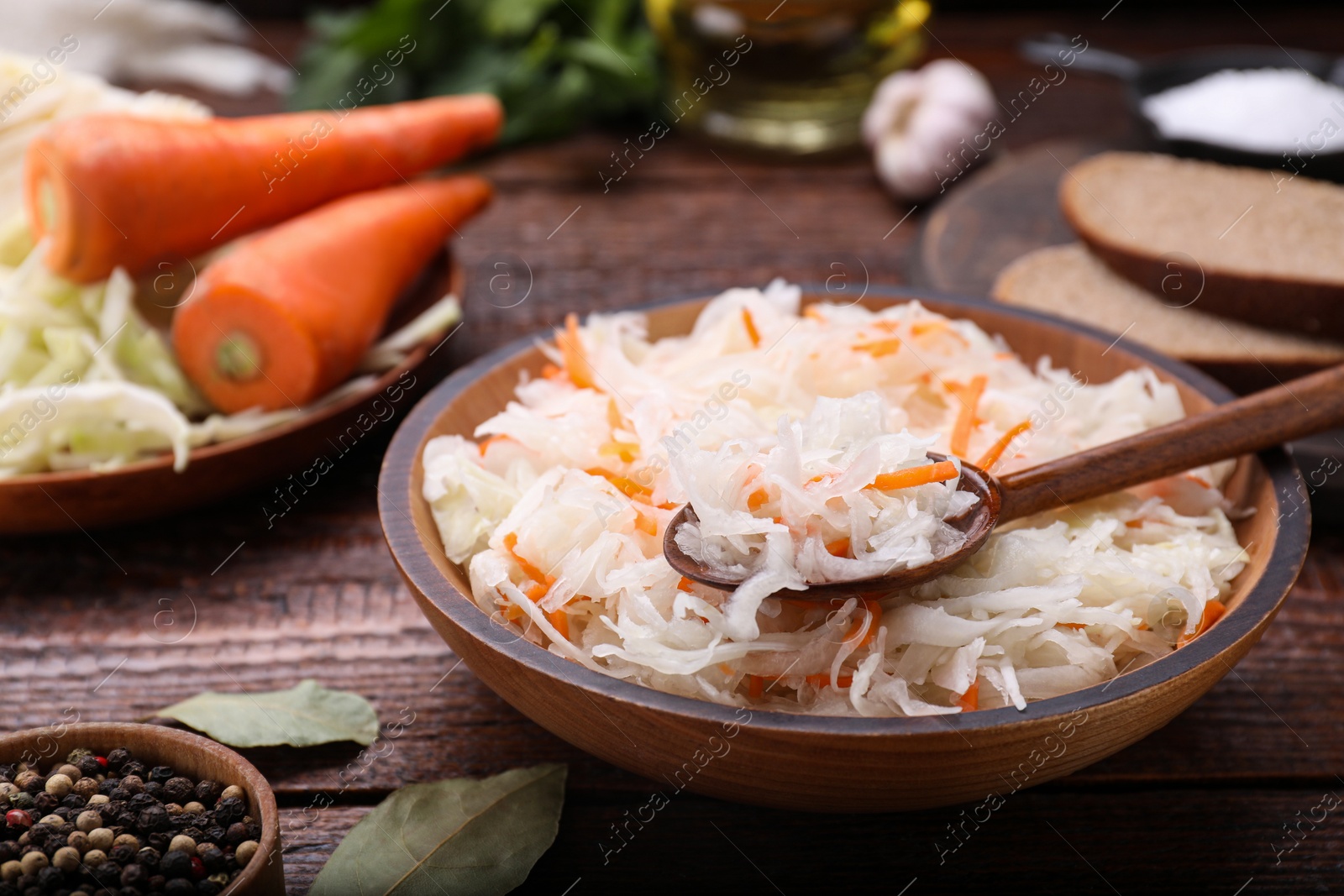 Photo of Bowl of tasty sauerkraut on wooden table, closeup