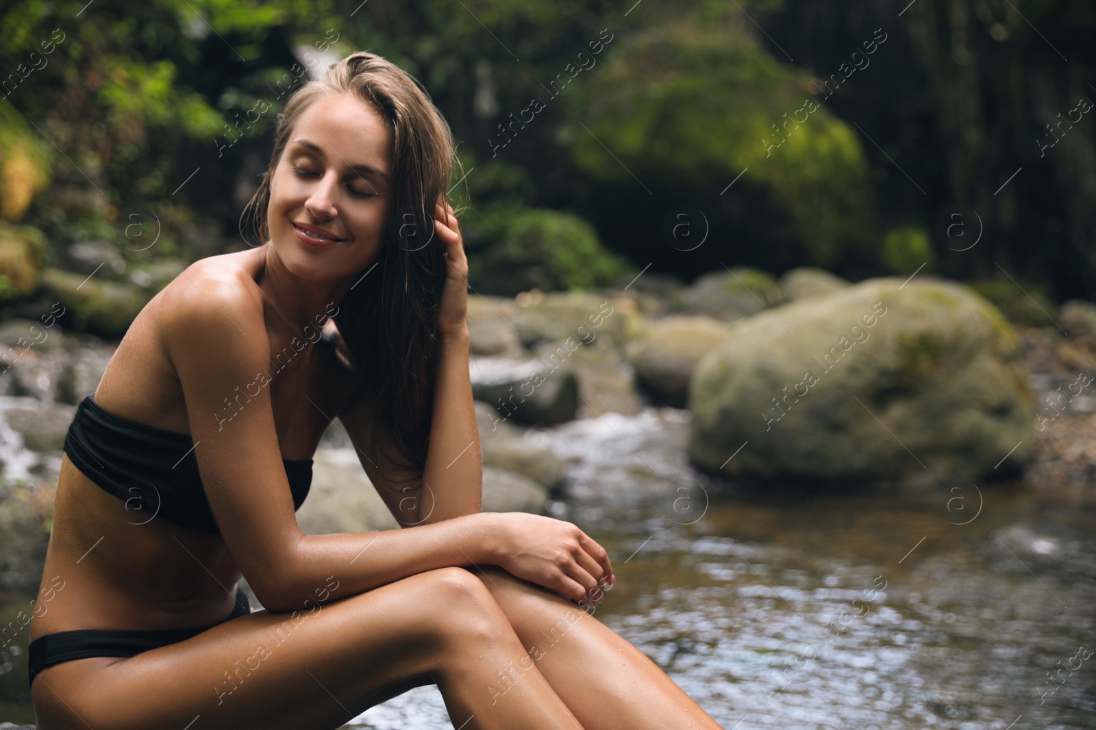 Photo of Beautiful young woman relaxing near mountain river outdoors. Space for text