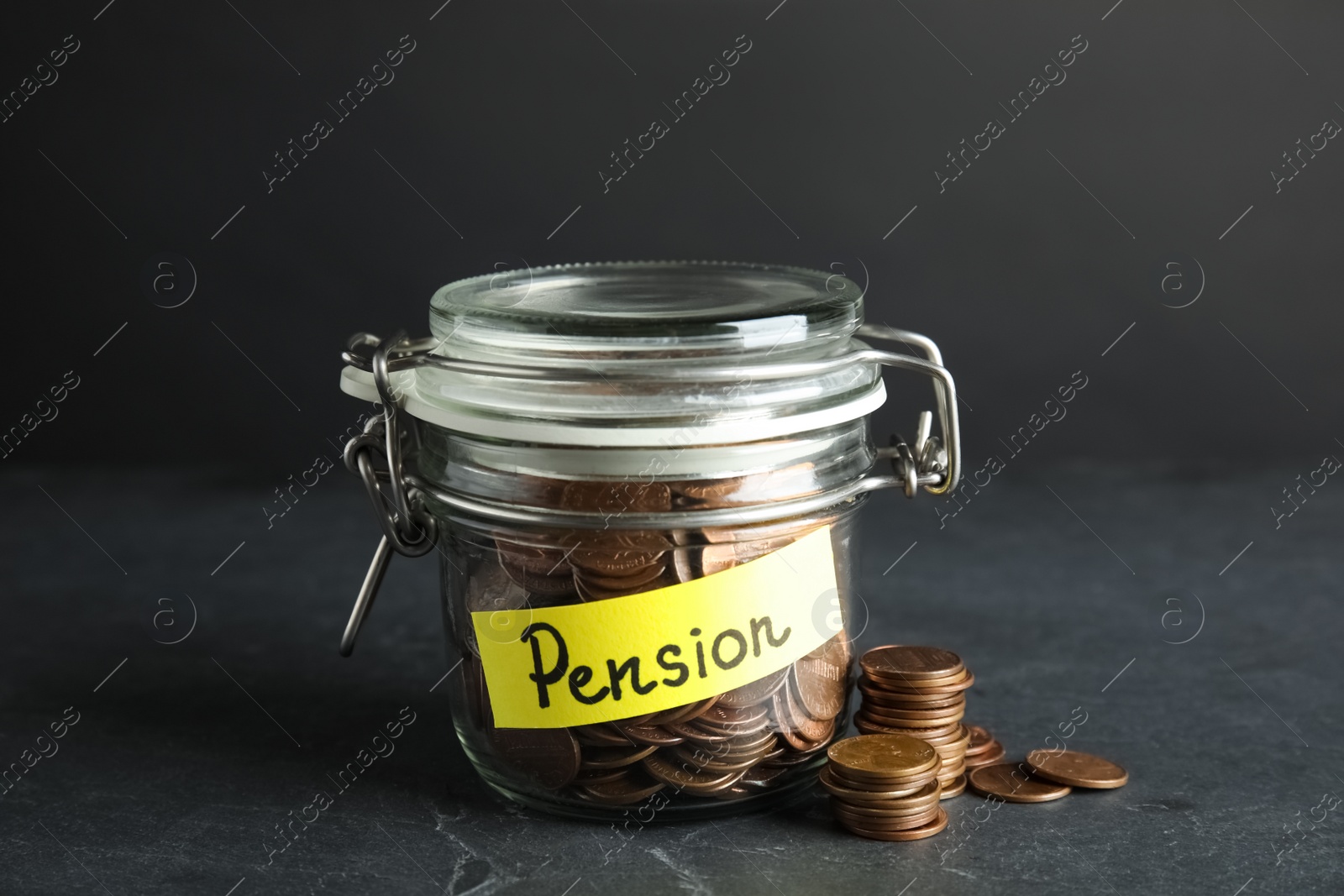 Photo of Glass jar with label PENSION and coins on dark table