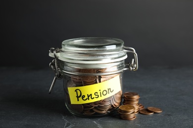 Glass jar with label PENSION and coins on dark table