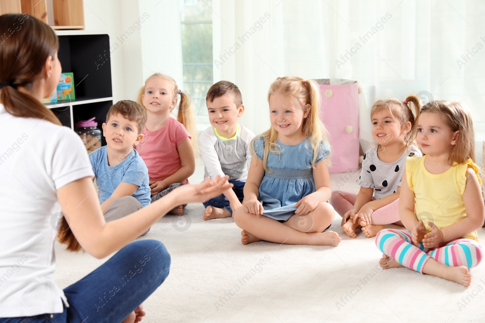 Photo of Kindergarten teacher and little children indoors. Learning and playing