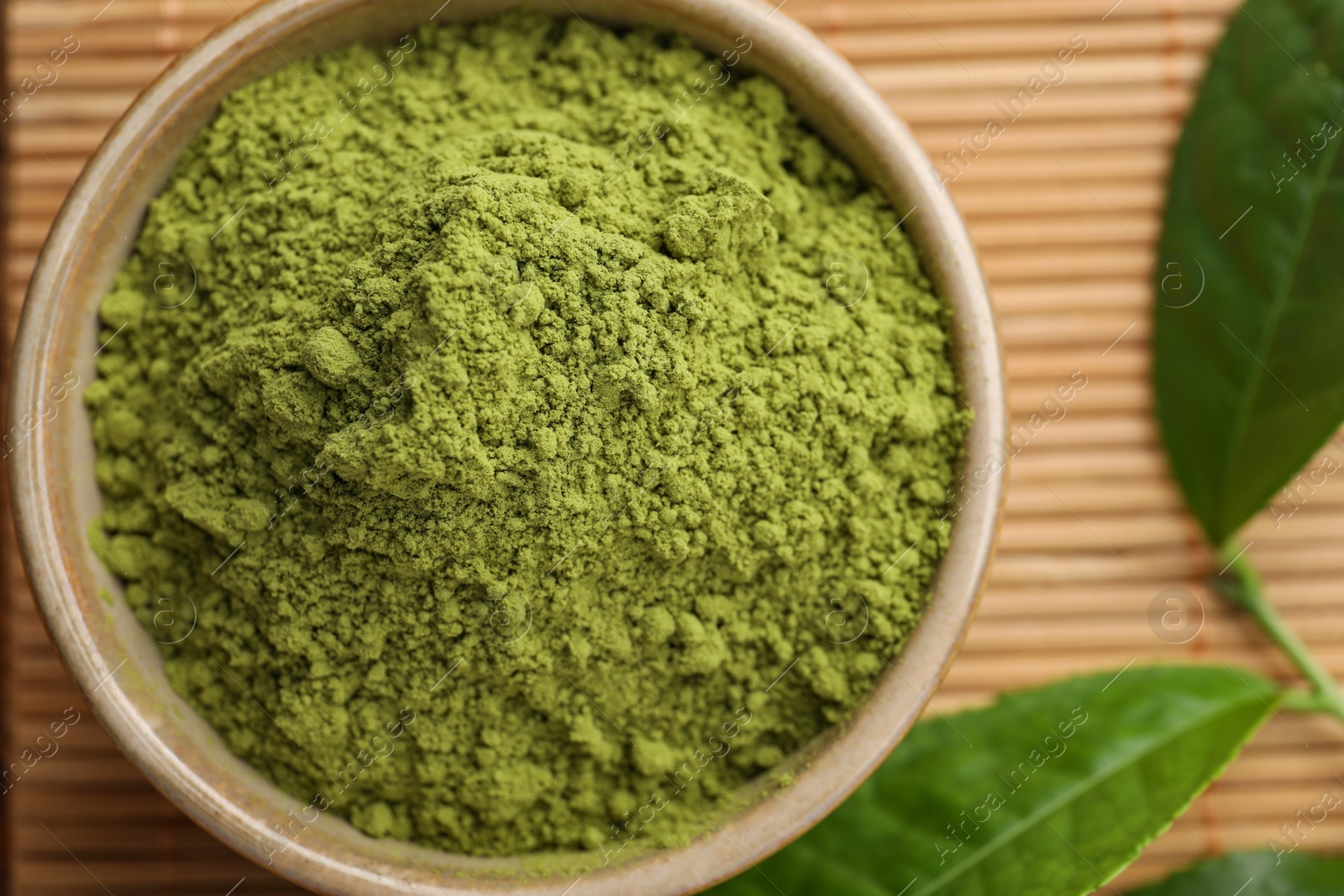Photo of Bowl of green matcha powder on bamboo mat, top view