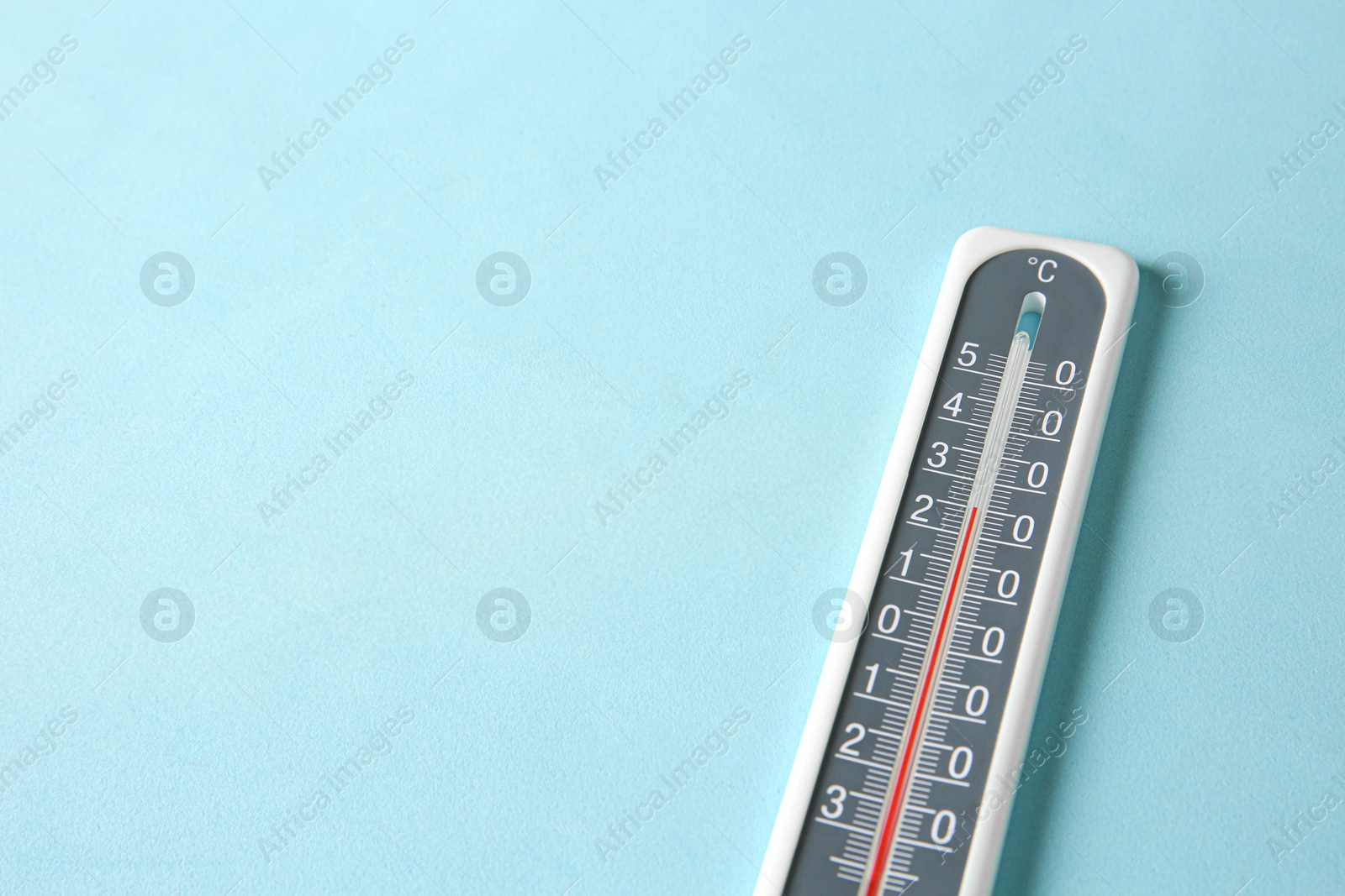 Photo of Weather thermometer on light blue background, closeup. Space for text