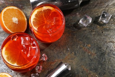 Photo of Aperol spritz cocktail, ice cubes and orange slices in glasses on grey textured table, above view. Space for text