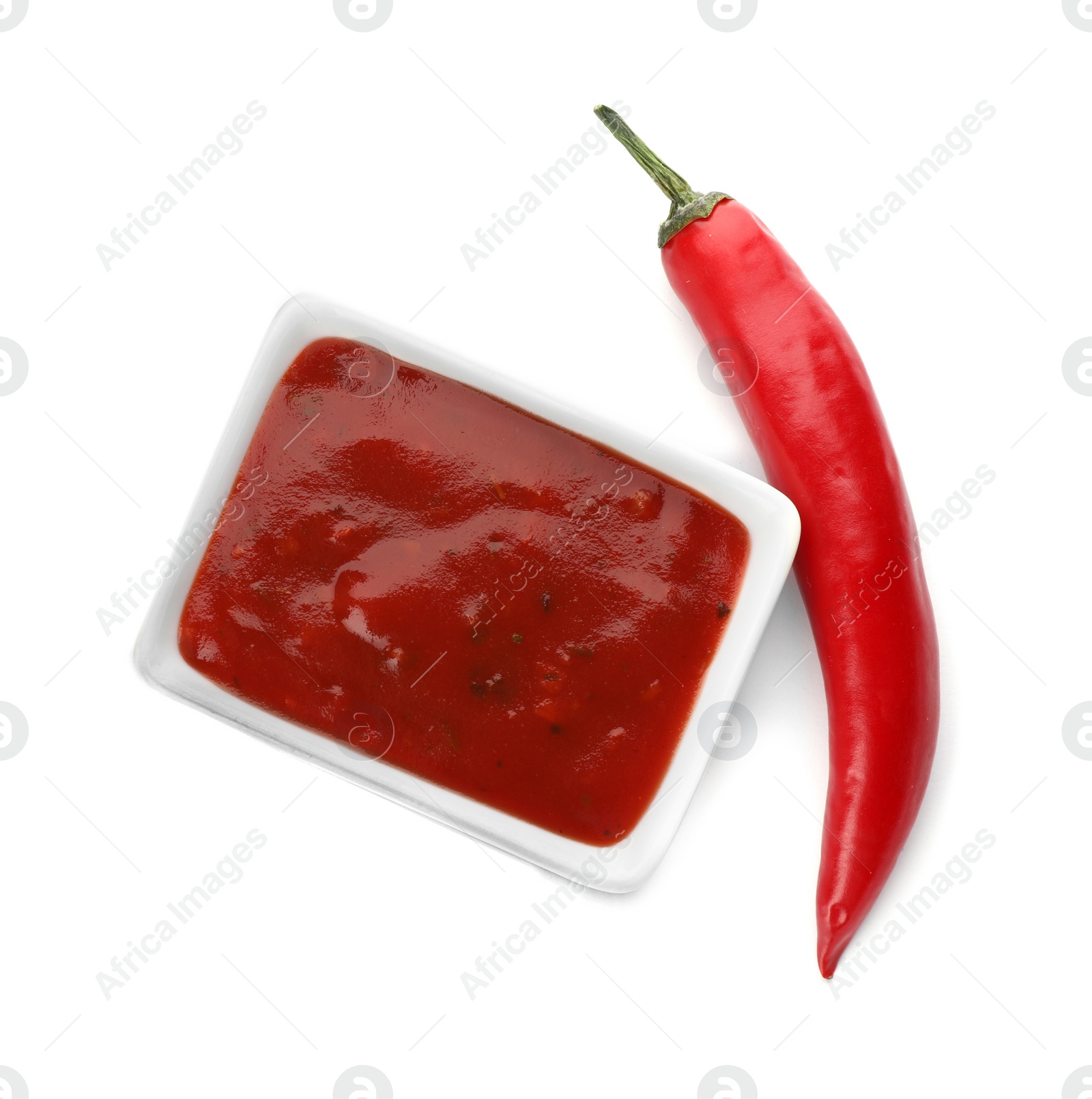 Photo of Bowl with spicy chili sauce and fresh pepper on white background, top view