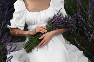 Photo of Woman with lavender bouquet sitting in field, closeup