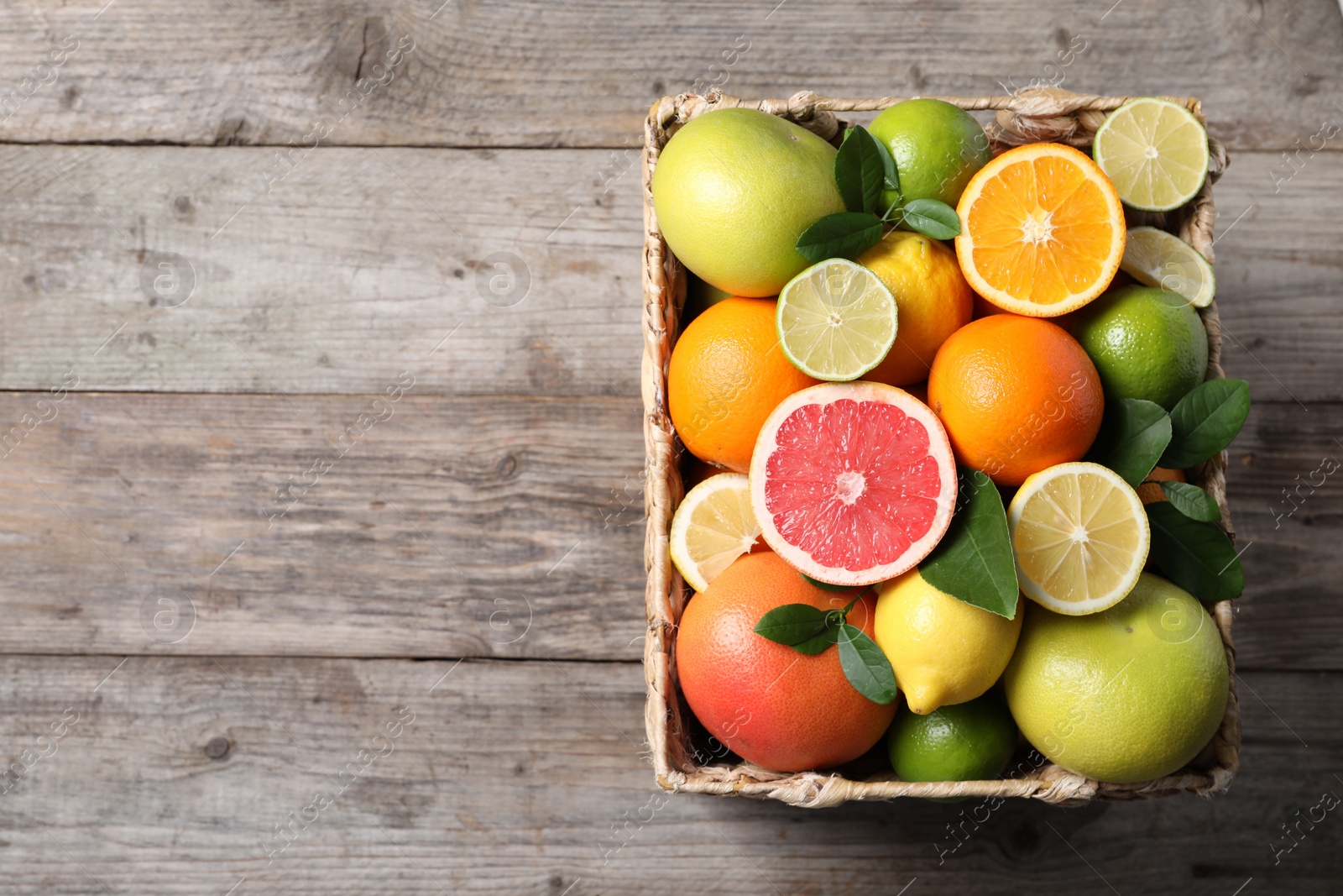 Photo of Different cut and whole citrus fruits on wooden table, top view. Space for text