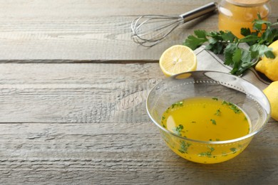 Photo of Bowl with lemon sauce and ingredients on wooden table, space for text. Delicious salad dressing