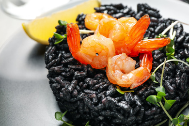 Photo of Delicious black risotto with shrimps in plate, closeup