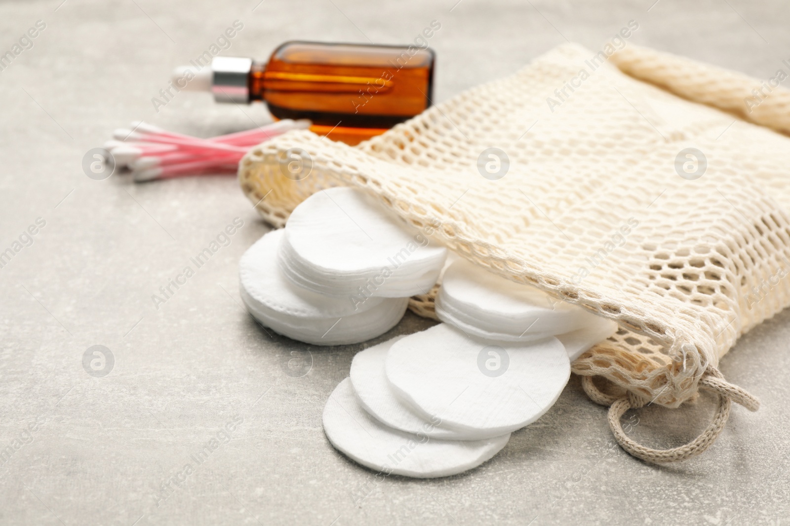 Photo of Cotton pads, swabs and makeup removal product on grey table, closeup