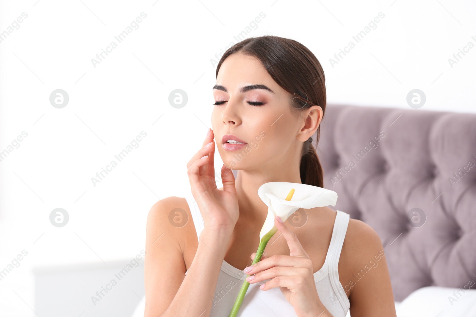 Photo of Portrait of young woman with calla flower indoors. Beauty and body care