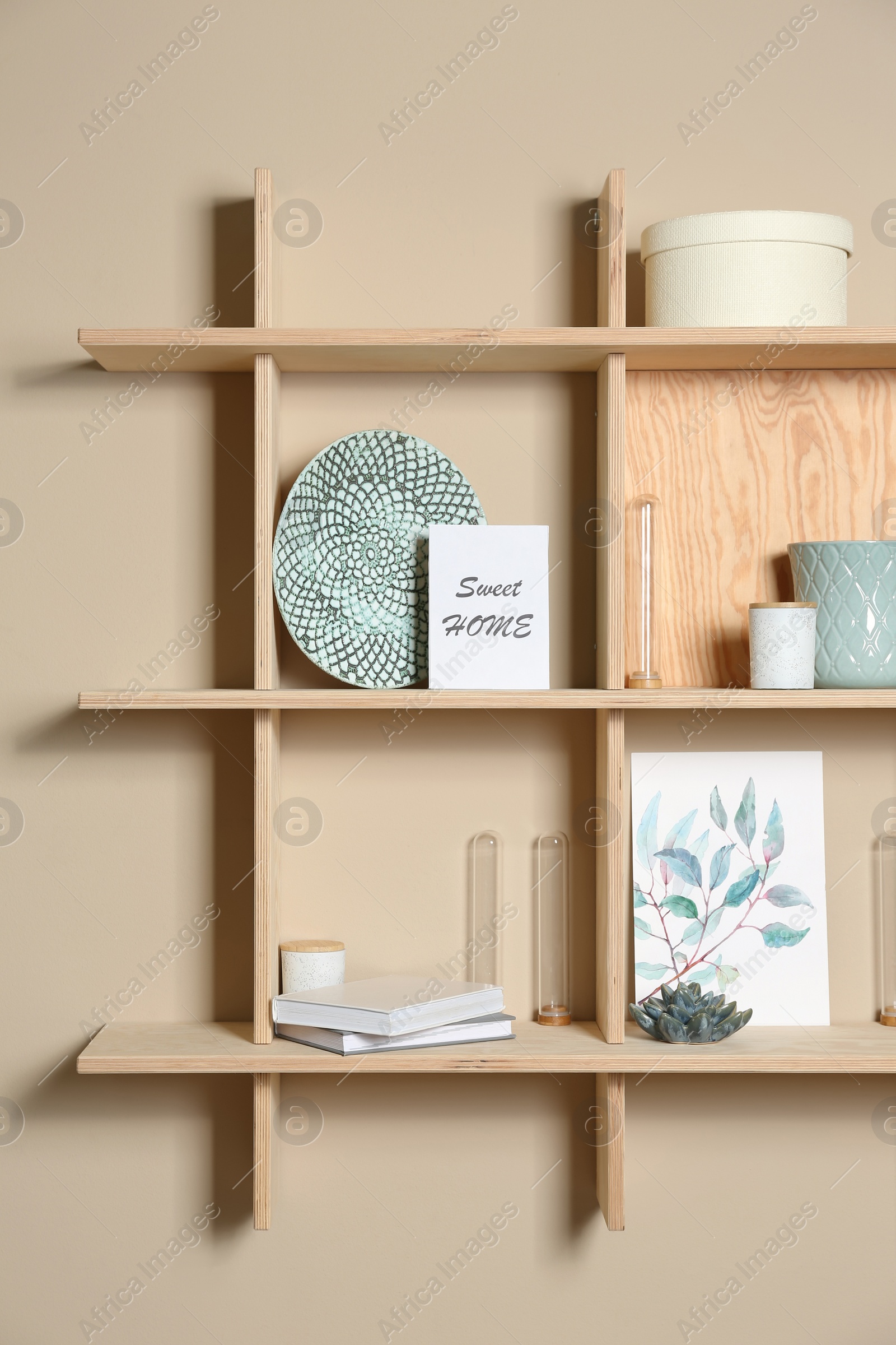 Photo of Wooden shelves with different decorative elements on beige wall