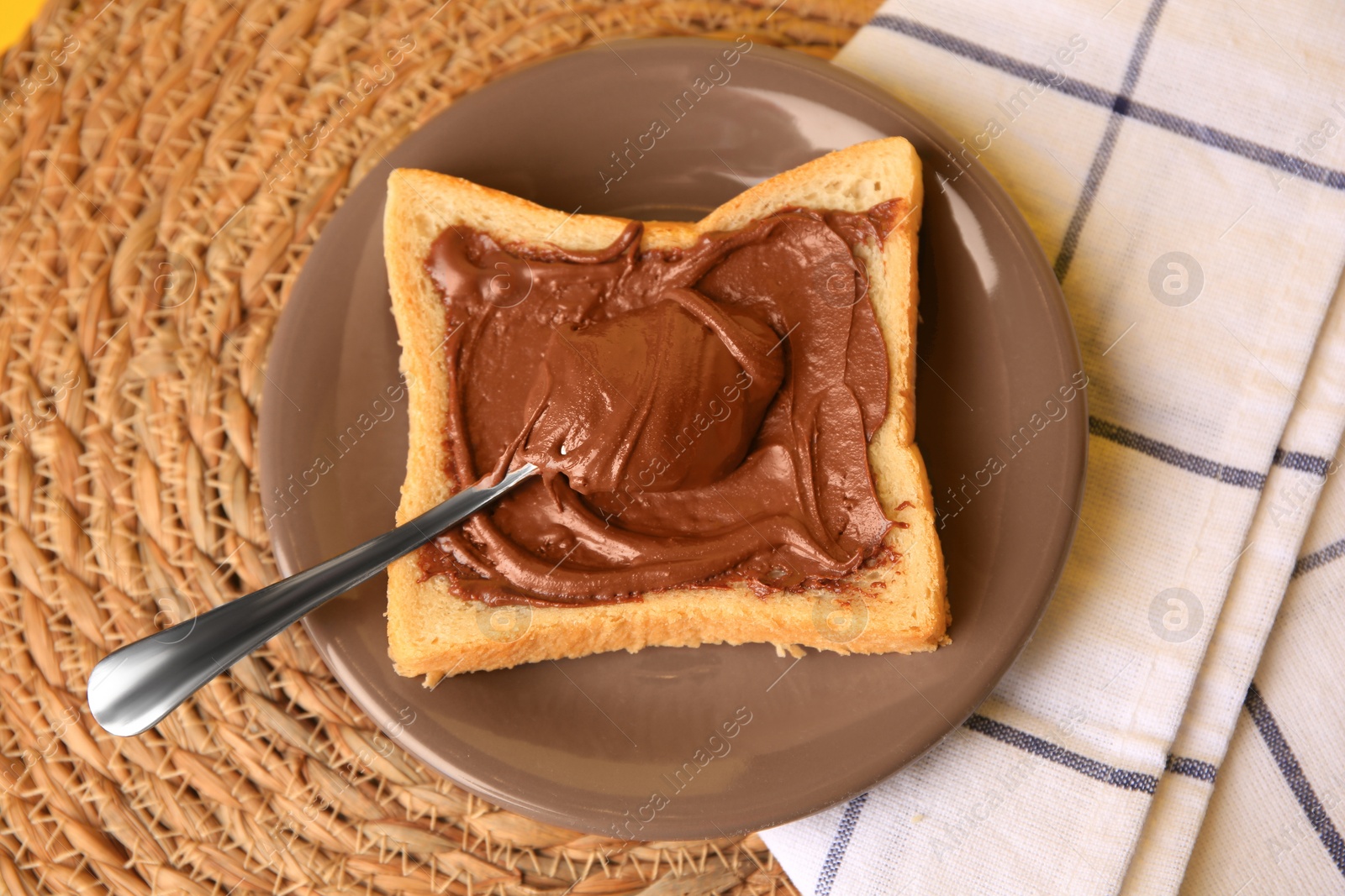 Photo of Tasty toast with chocolate paste on wicker mat, above view