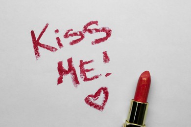 Photo of Phrase Kiss Me and red heart made with lipstick on white background, above view