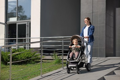 Beautiful nanny with cute little boy in stroller walking on city street
