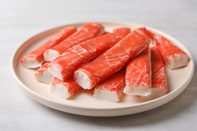 Plate of fresh crab sticks on white table, closeup