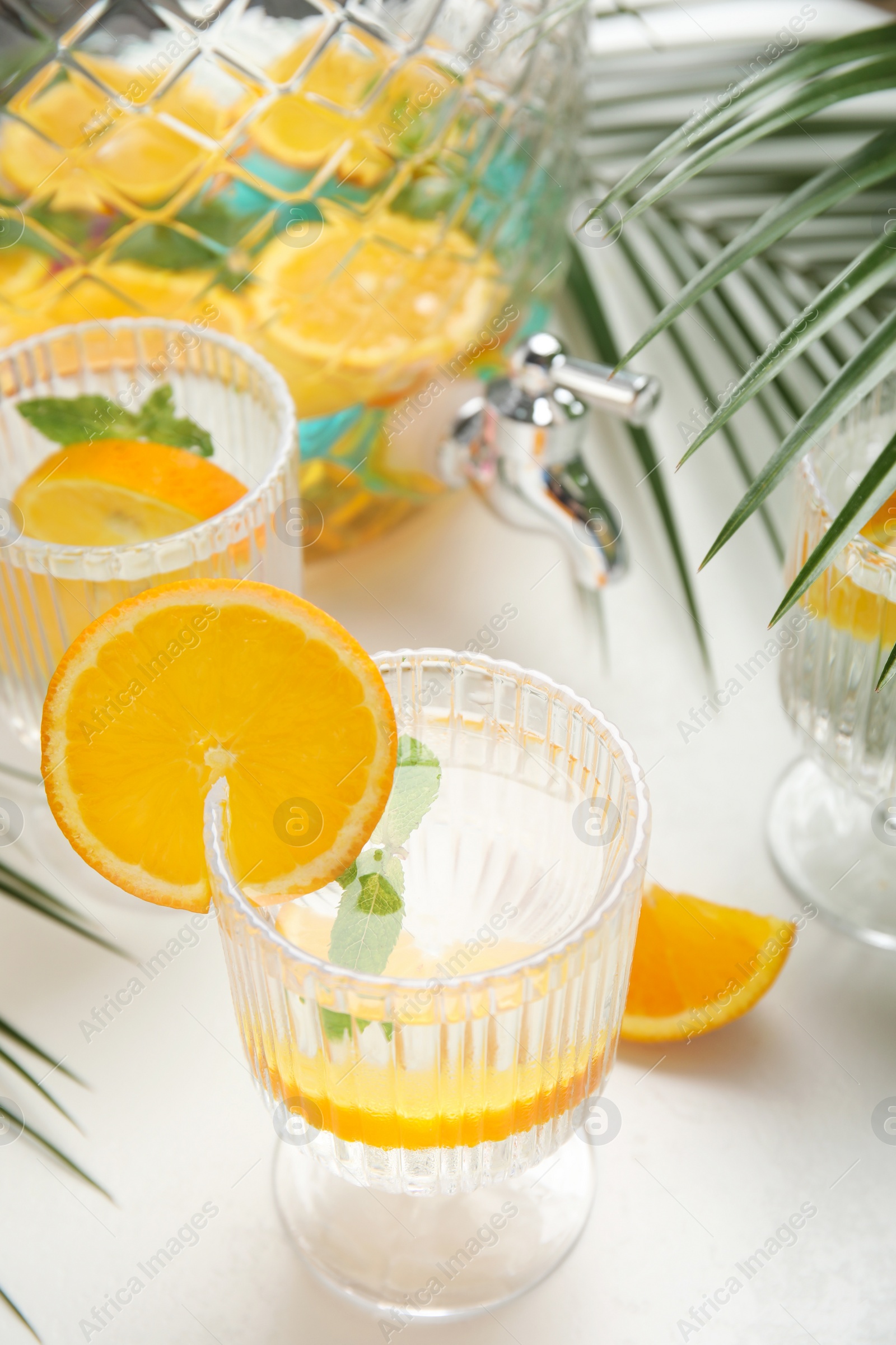 Photo of Delicious refreshing drink with orange and mint on white table