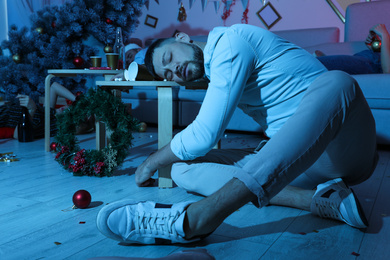 Drunk man sleeping at table in messy room after New Year party