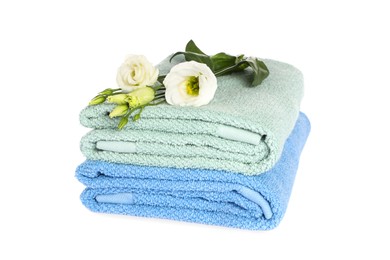 Photo of Folded clean soft towels with flowers isolated on white