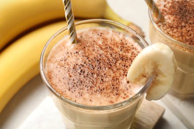 Tasty banana smoothie with chocolate and fresh fruits on white marble table, closeup