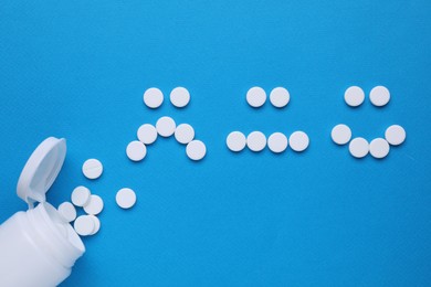 Photo of Sad and happy emoticons made of antidepressants and bottle on blue background, flat lay