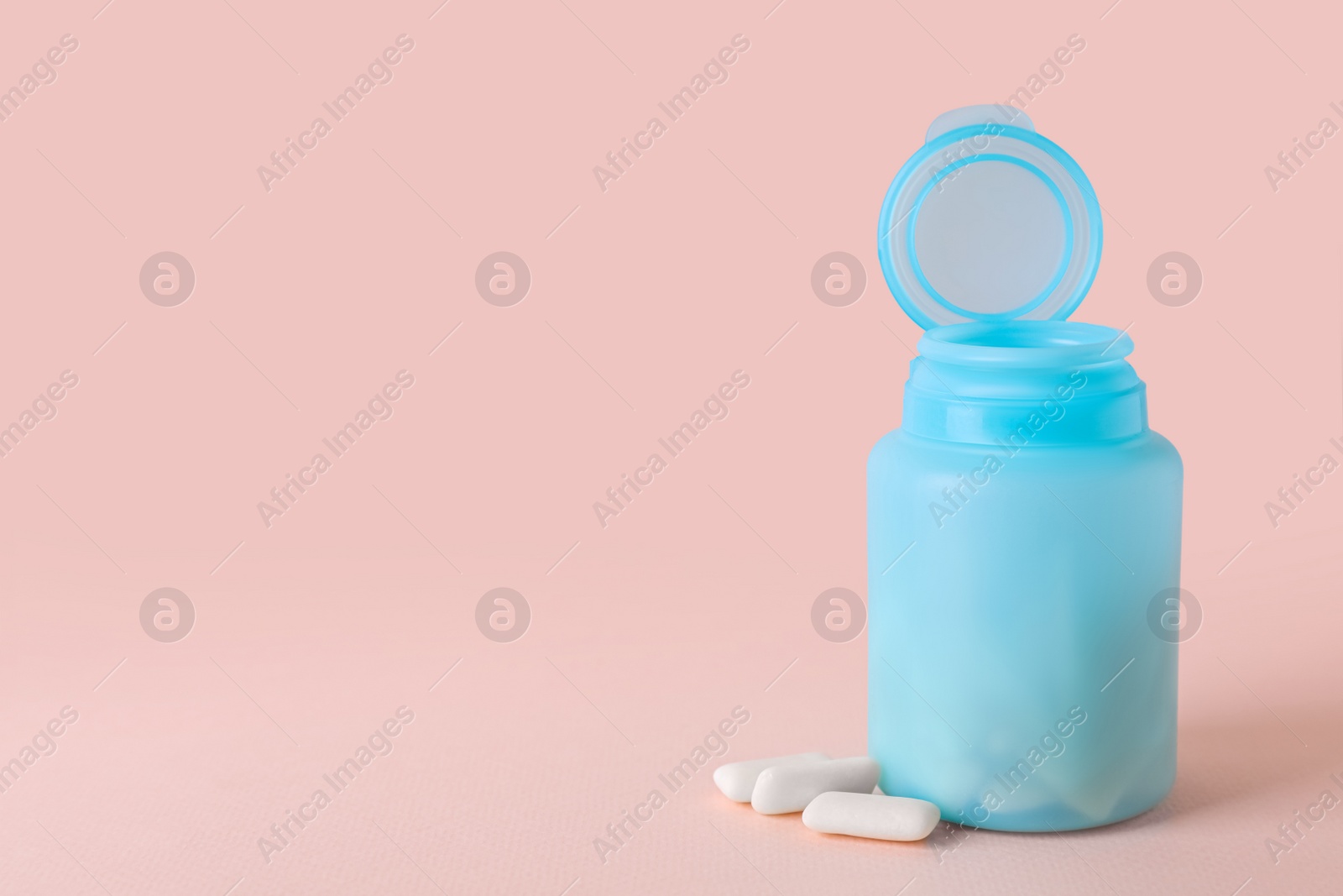 Photo of Jar with chewing gums on light pink background. Space for text